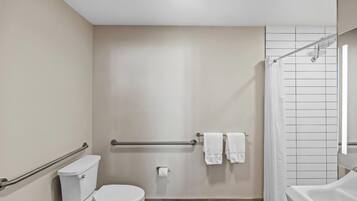 A modern bathroom with a toilet, grab bar, shower, and bathtub.