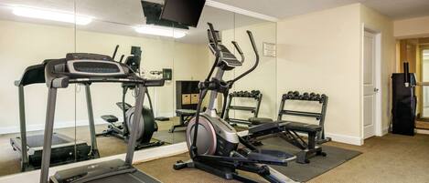 A gym with treadmills, an elliptical, and a bench.