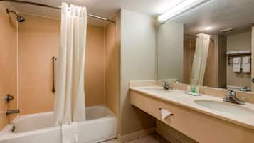 A bathroom with a bathtub, two sinks, a mirror, and a shower curtain.