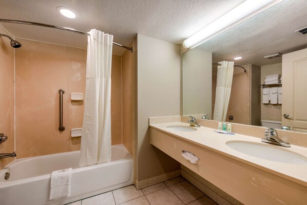Un baño con bañera, dos lavamanos, un espejo y cortina de ducha.