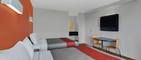 Hotellihuone, jossa on kaksi sänkyä, työpöytä, tuoli, televisio ja seinään kiinnitetty valaisin.