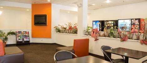 A modern indoor space with a seating area, a television mounted on the wall, and a display of magazines.