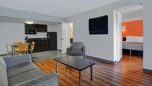 Un appartement moderne comprenant un coin repas, une kitchenette, un salon et une chambre avec un mur d’accent orange.