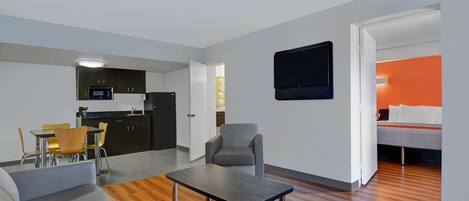 Apartamento moderno com área de refeições, cozinha compacta, sala de estar e um quarto com parede de destaque laranja.