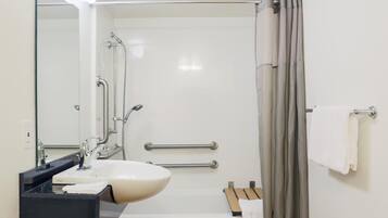 Un baño moderno con un lavabo blanco, un espejo, una ducha con puerta de cristal y un perchero para toallas.
