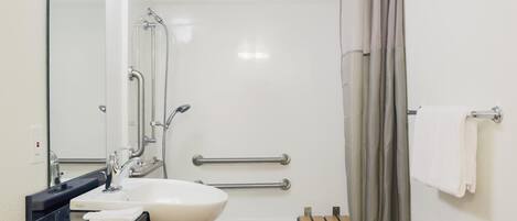 A modern bathroom with a white sink, a mirror, a shower with a glass door, and a towel rack.