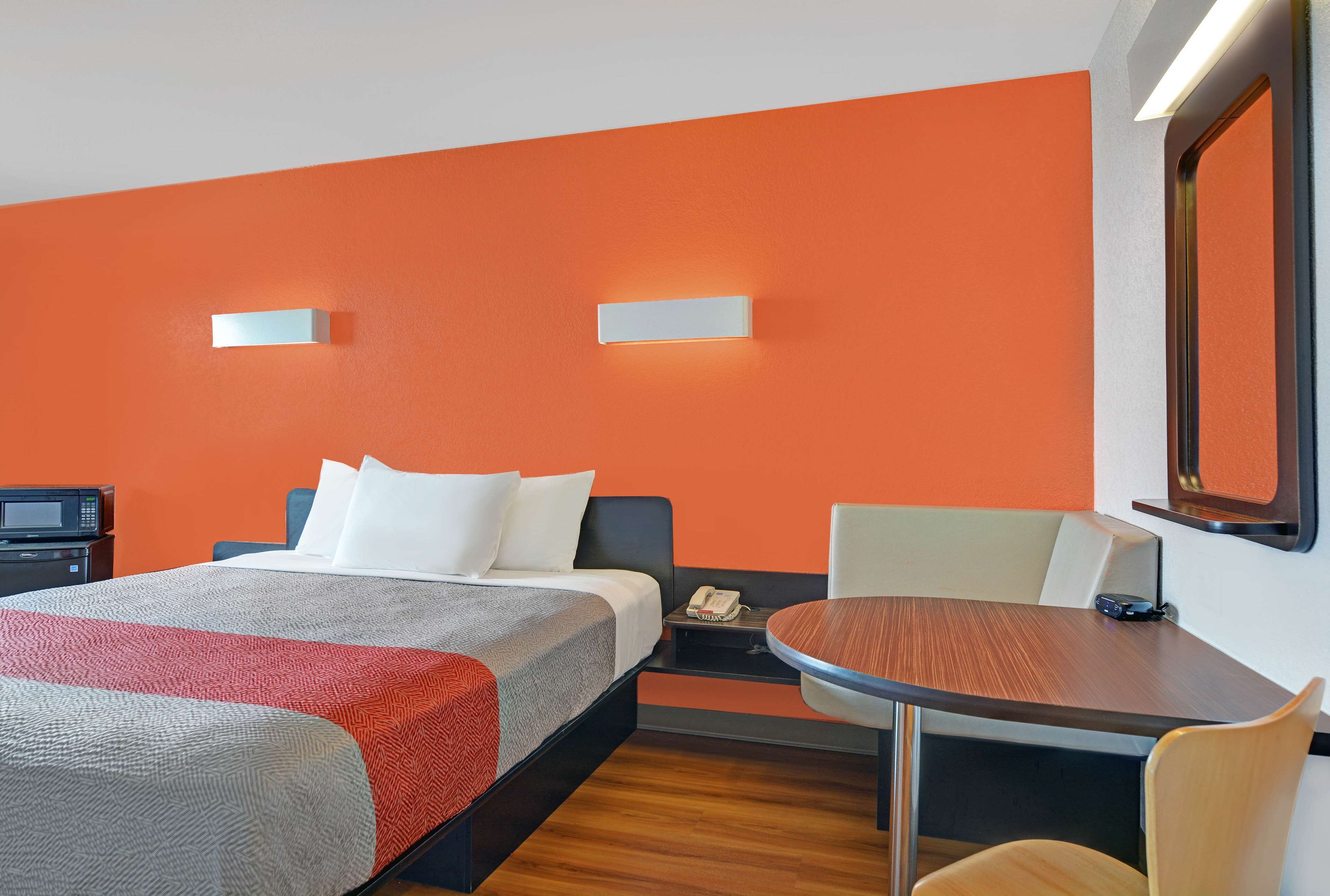 A hotel room with a bed, bedside table, chair, and a small table with a chair.