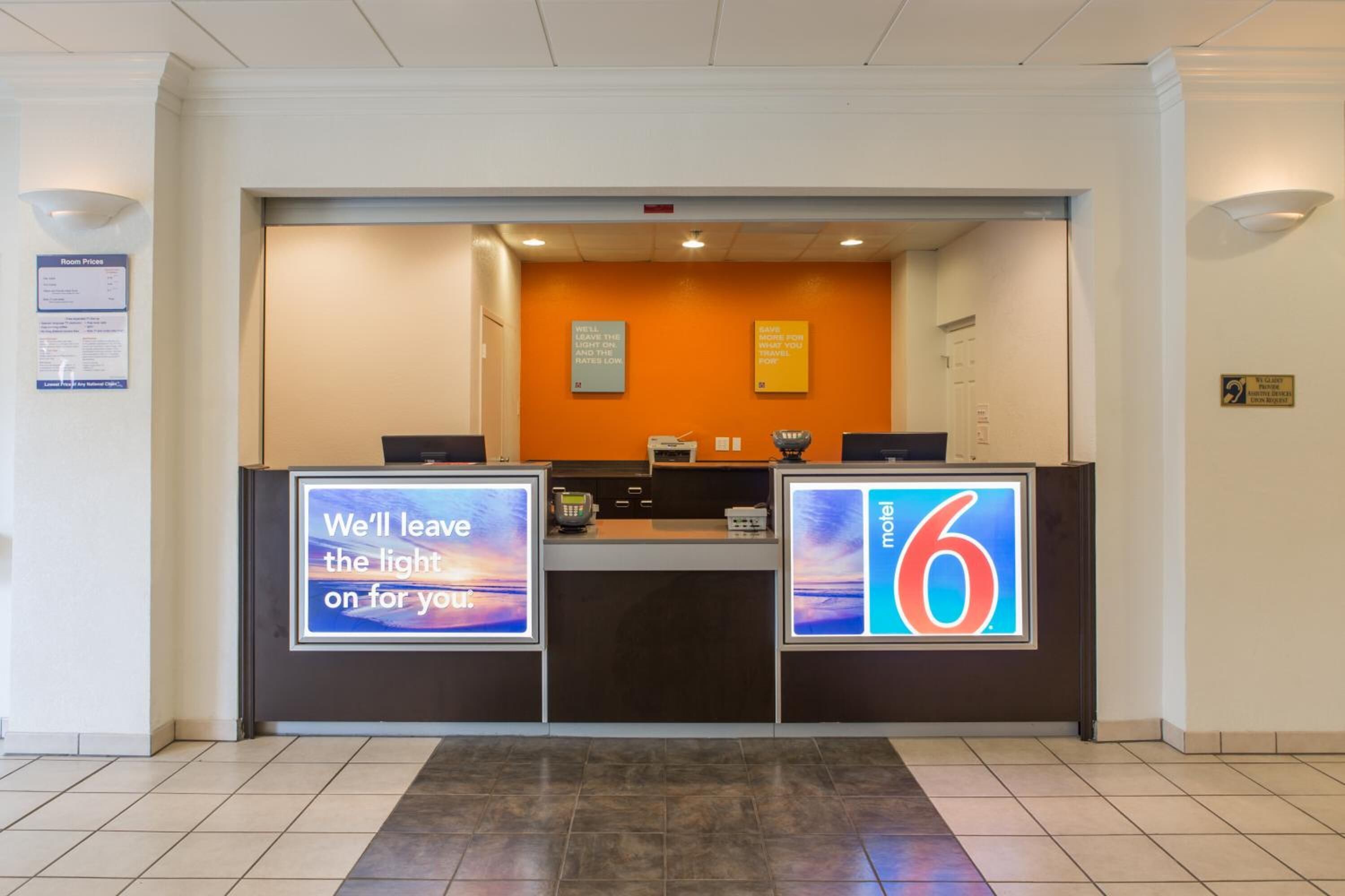 A hotel reception desk with a digital display, a room price sign, and a number 6 sign.