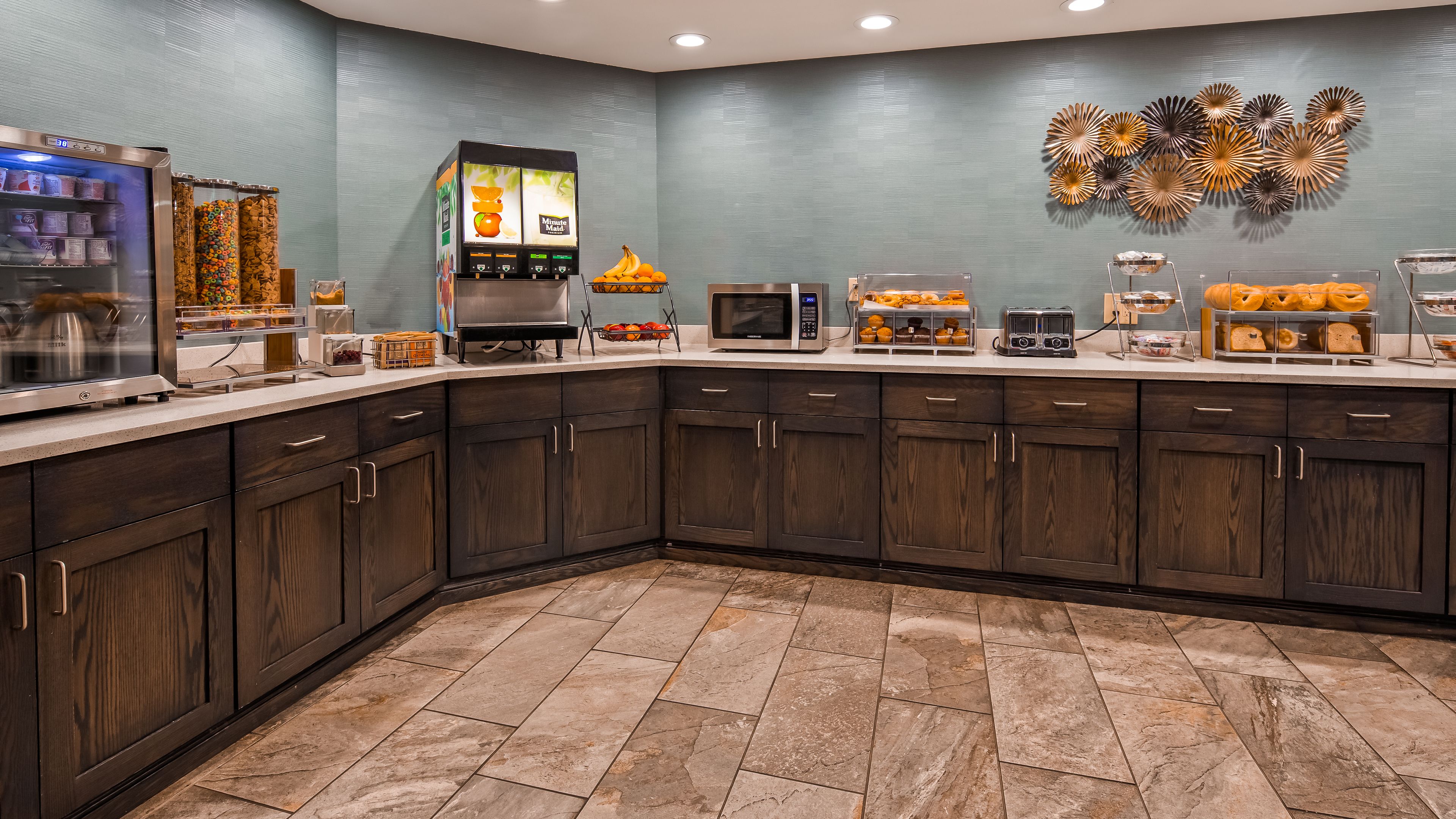 Una cucina moderna con mobili in legno scuro, un forno a microonde, una macchina per il caffè e un espositore per frutta.