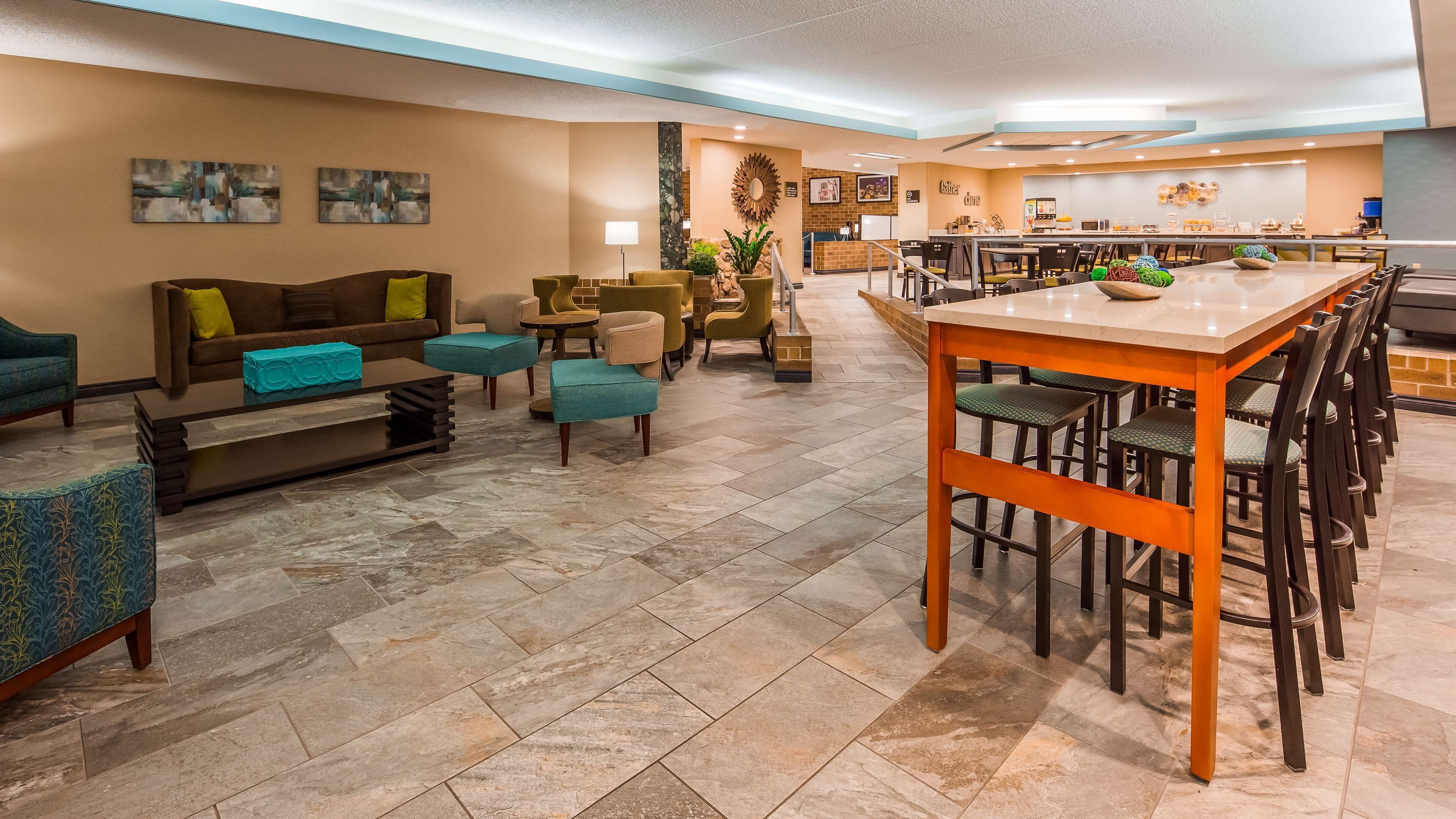 A modern hotel lobby with a seating area, a bar, and a dining space.