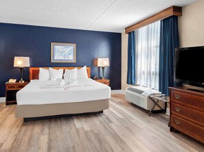 A hotel room with a large bed, two bedside lamps, a flat-screen TV, a dresser, and a window with curtains. - Best Western Potomac Mills (Woodbridge)