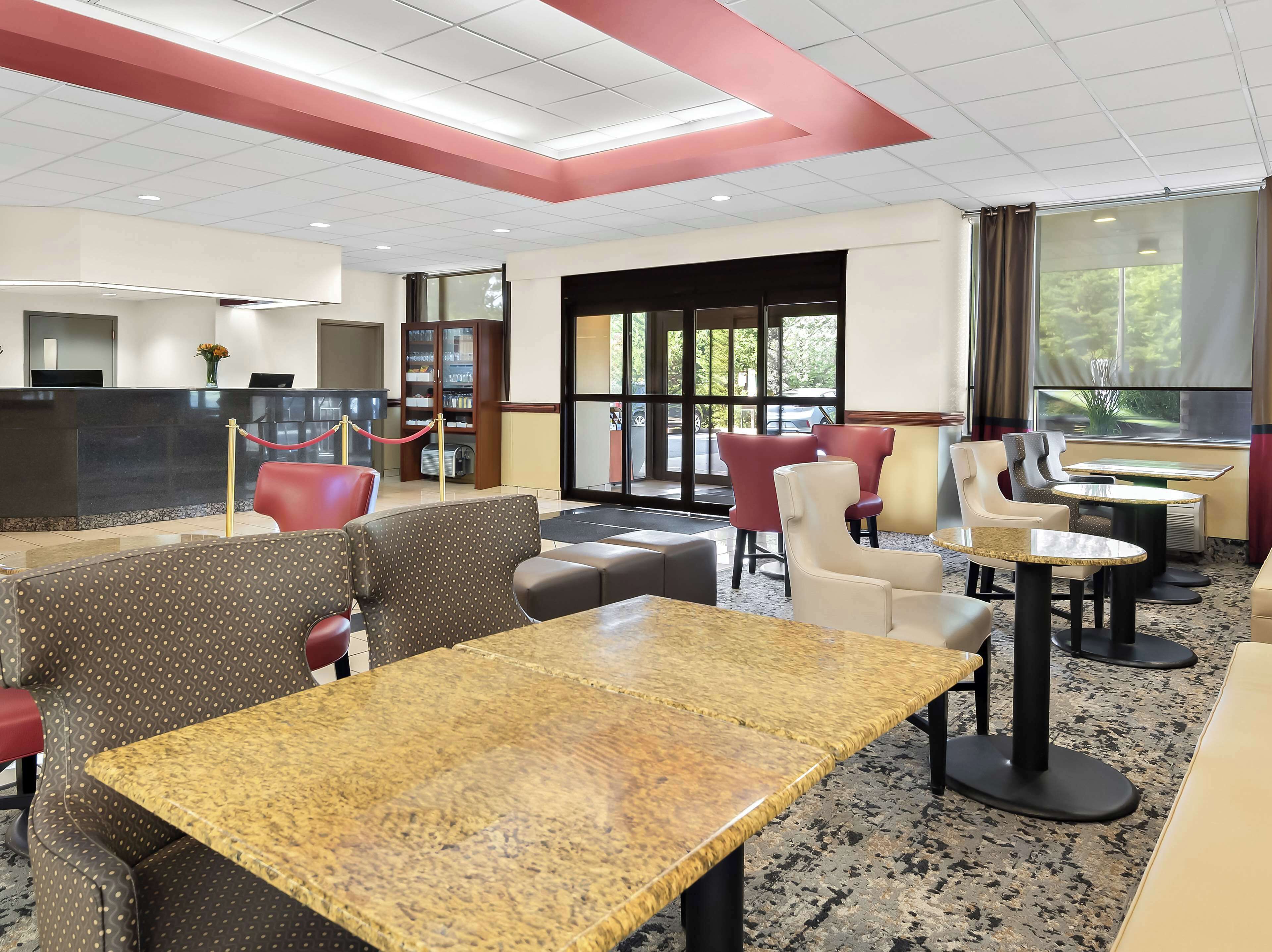 Eine Hotelhalle mit Sitzbereichen, einer Rezeption und großen Fenstern.