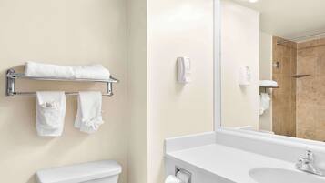 Une salle de bain comprenant des toilettes, un lavabo, un porte-serviettes avec des serviettes, un miroir et un espace douche.