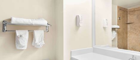 Een badkamer met toilet, wastafel, handdoekrek met handdoeken, spiegel en douche.