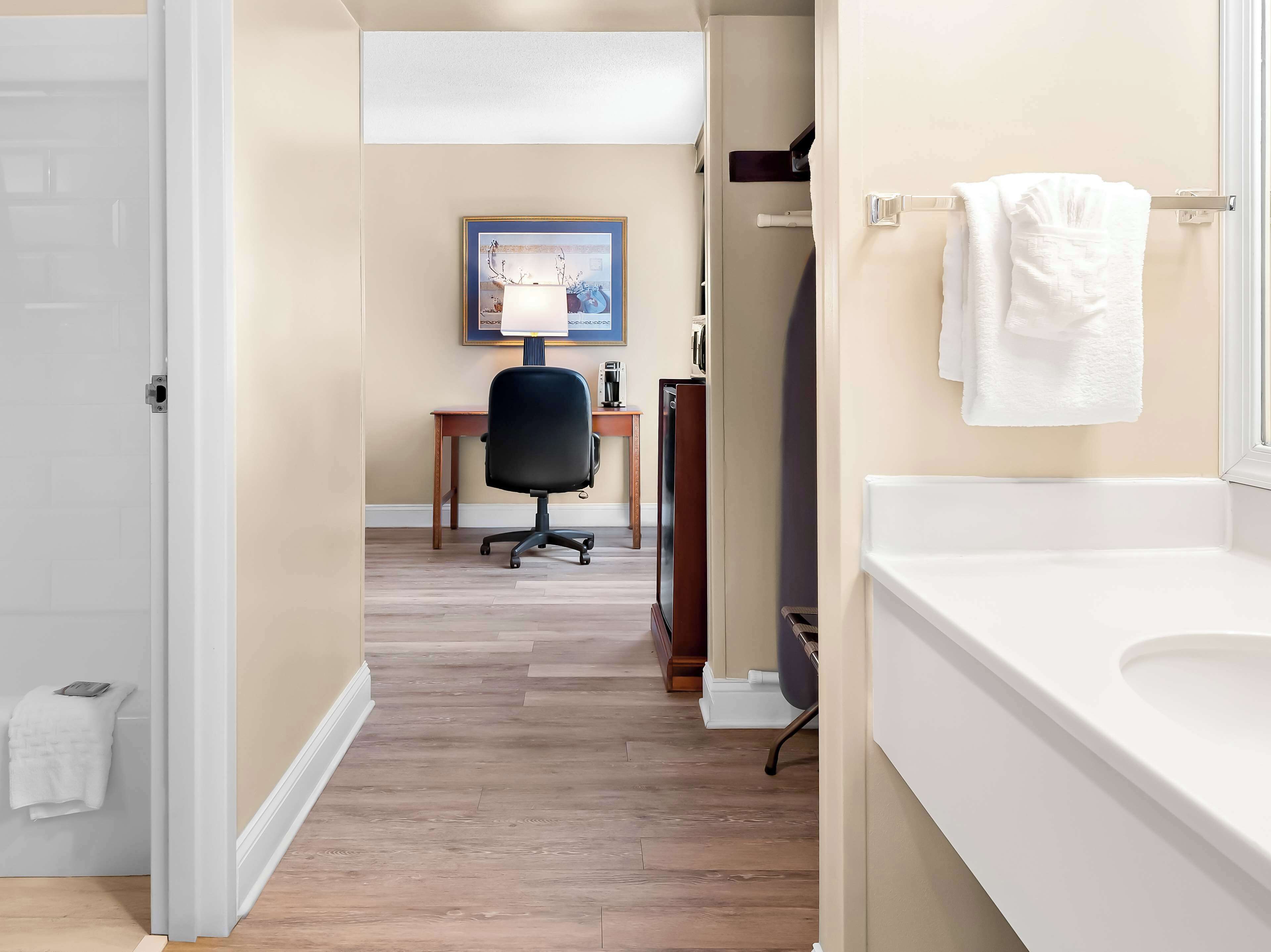 A hotel bathroom with a white sink, a mirror, and a towel rack.