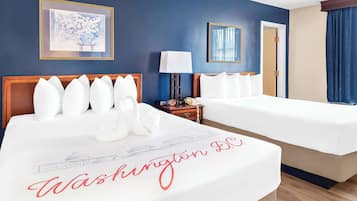 A hotel room with two beds, a nightstand with a lamp, a framed picture on the wall, and a door with a curtain.