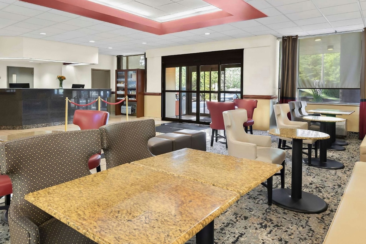 A hotel lobby with a reception desk, seating area, and large windows.