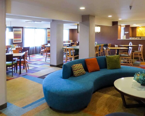 Un espace détente moderne avec un canapé bleu, une table ronde et un tapis coloré.