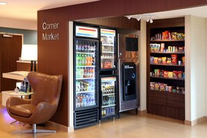 A corner market with a vending machine, a refrigerator stocked with beverages, and shelves of snacks. - Quality Inn Cranberry Township (Cranberry Township)