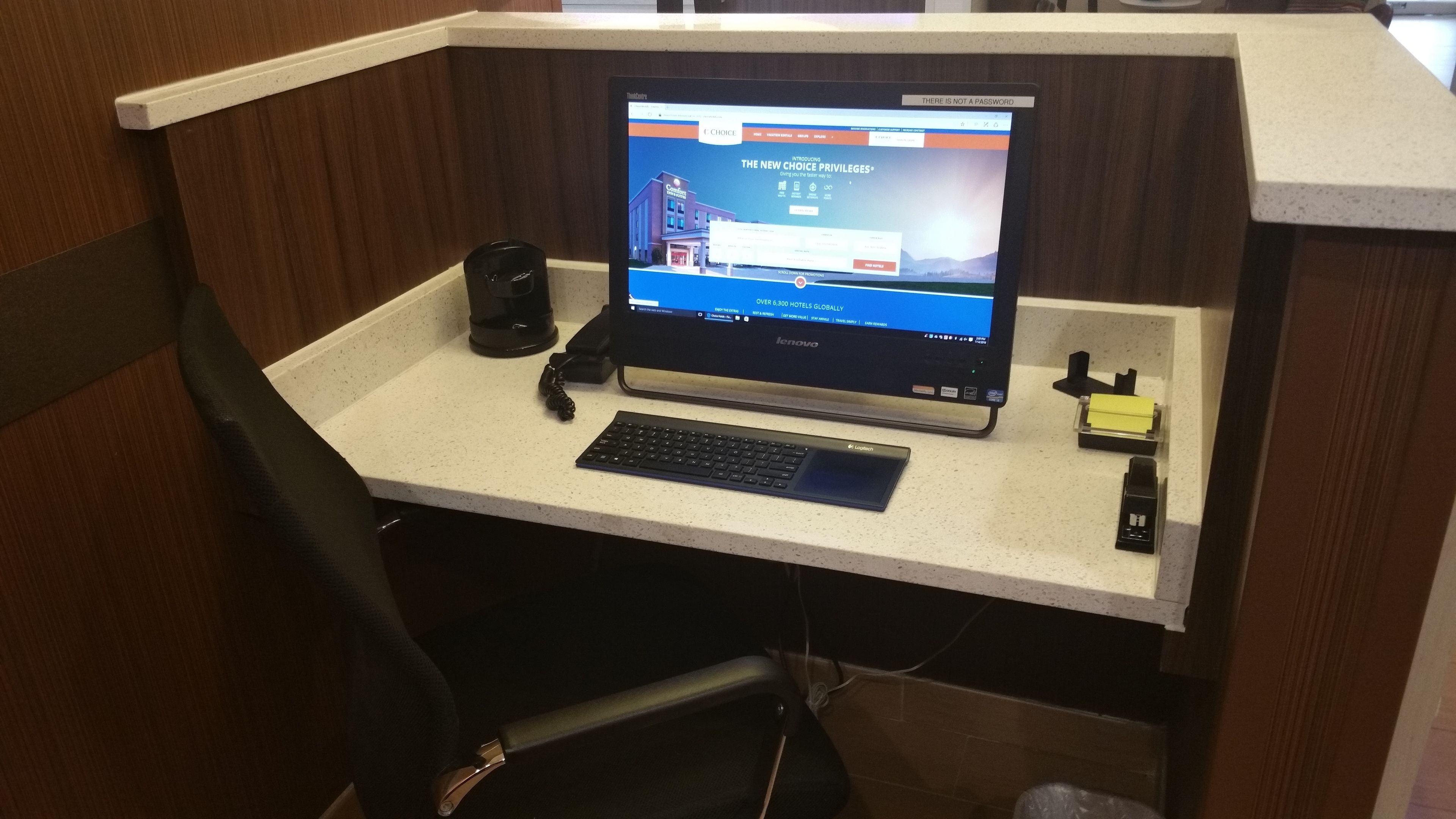 A Lenovo laptop on a white desk with a keyboard, a mouse, and a coffee maker.