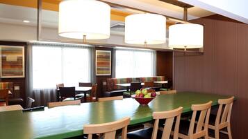 A dining area with a long table, multiple chairs, and a bowl of fruit.