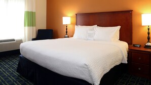 A hotel room with a large bed, two bedside lamps, a nightstand, and a chair. - Quality Inn Cranberry Township (Cranberry Township)