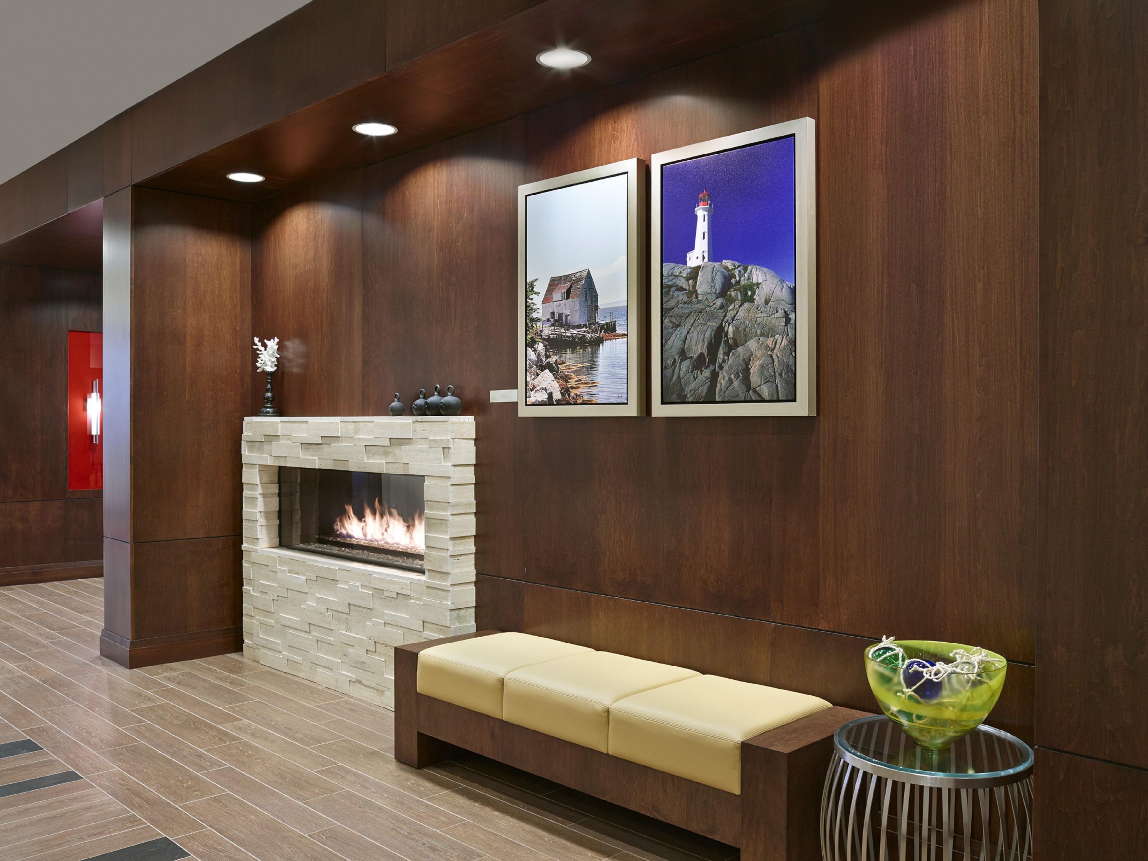 Un hall con chimenea de piedra, un banco y dos cuadros enmarcados en la pared.