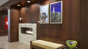 Un hall con chimenea de piedra, un banco y dos cuadros enmarcados en la pared.
