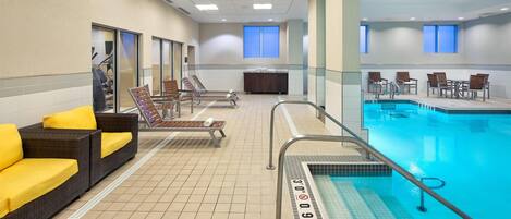 A hotel pool area with lounge chairs, a seating area, and a lifeguard stand.