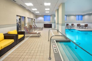 A hotel pool area with lounge chairs, a seating area, and a lifeguard stand.