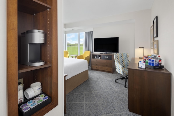 Une chambre d’hôtel équipée d’un lit, d’un bureau avec un téléviseur à écran plat, d’une machine à café, d’un mini-bar et offrant une vue sur l’extérieur.