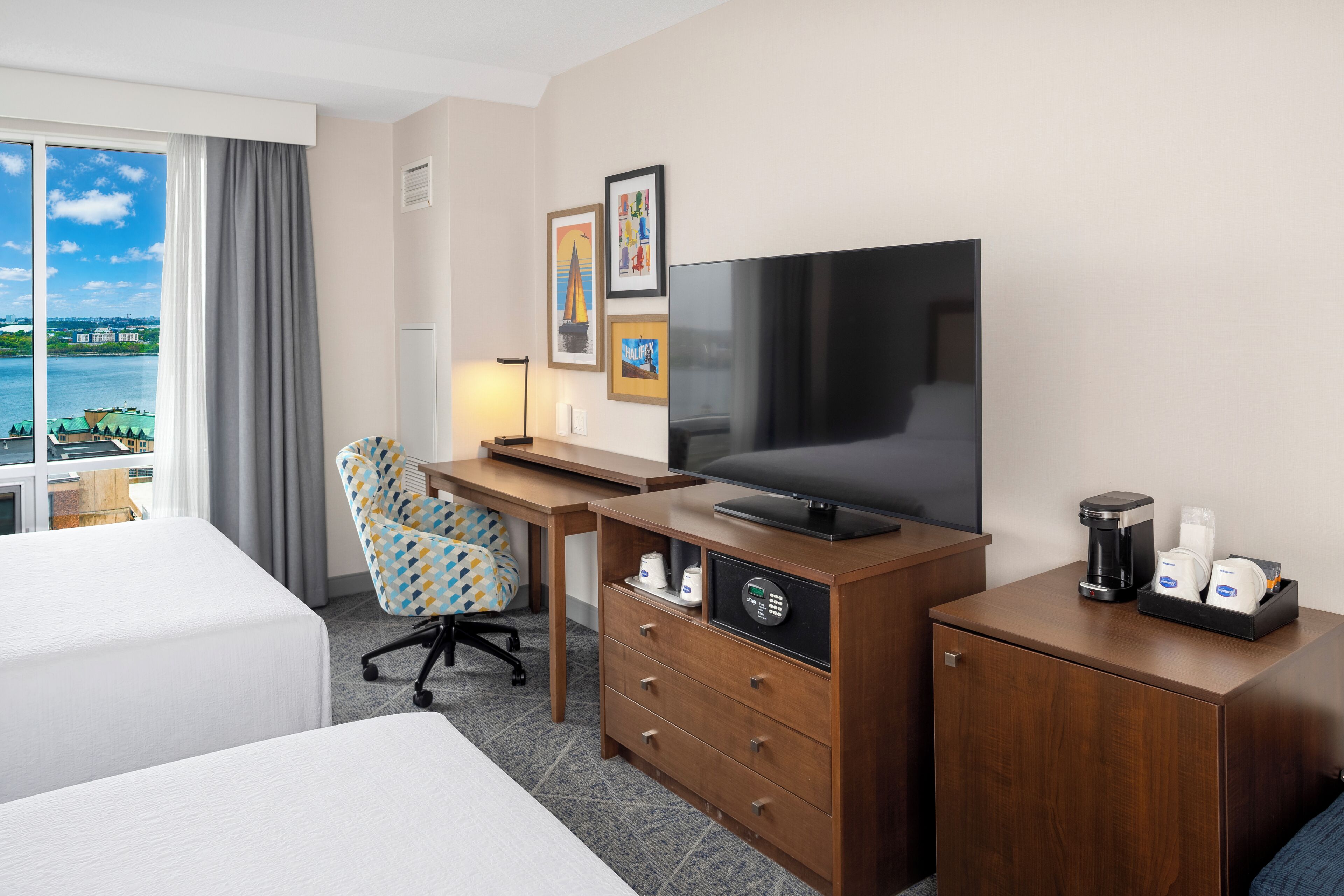 Une chambre d’hôtel équipée d’un lit, d’un bureau avec une télévision, d’une chaise et d’une machine à café.