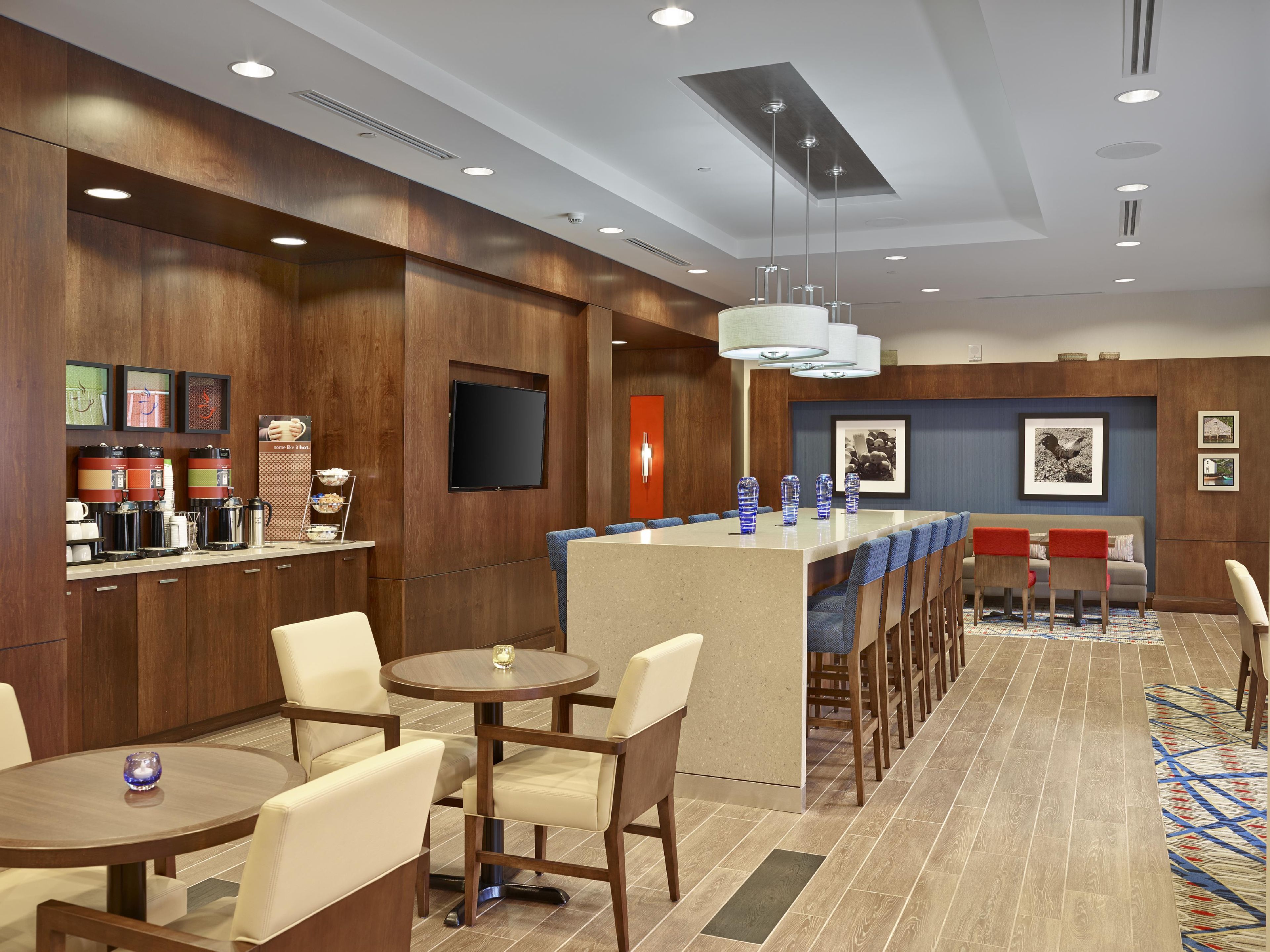 A hotel lobby with a bar area, seating, and a television screen.