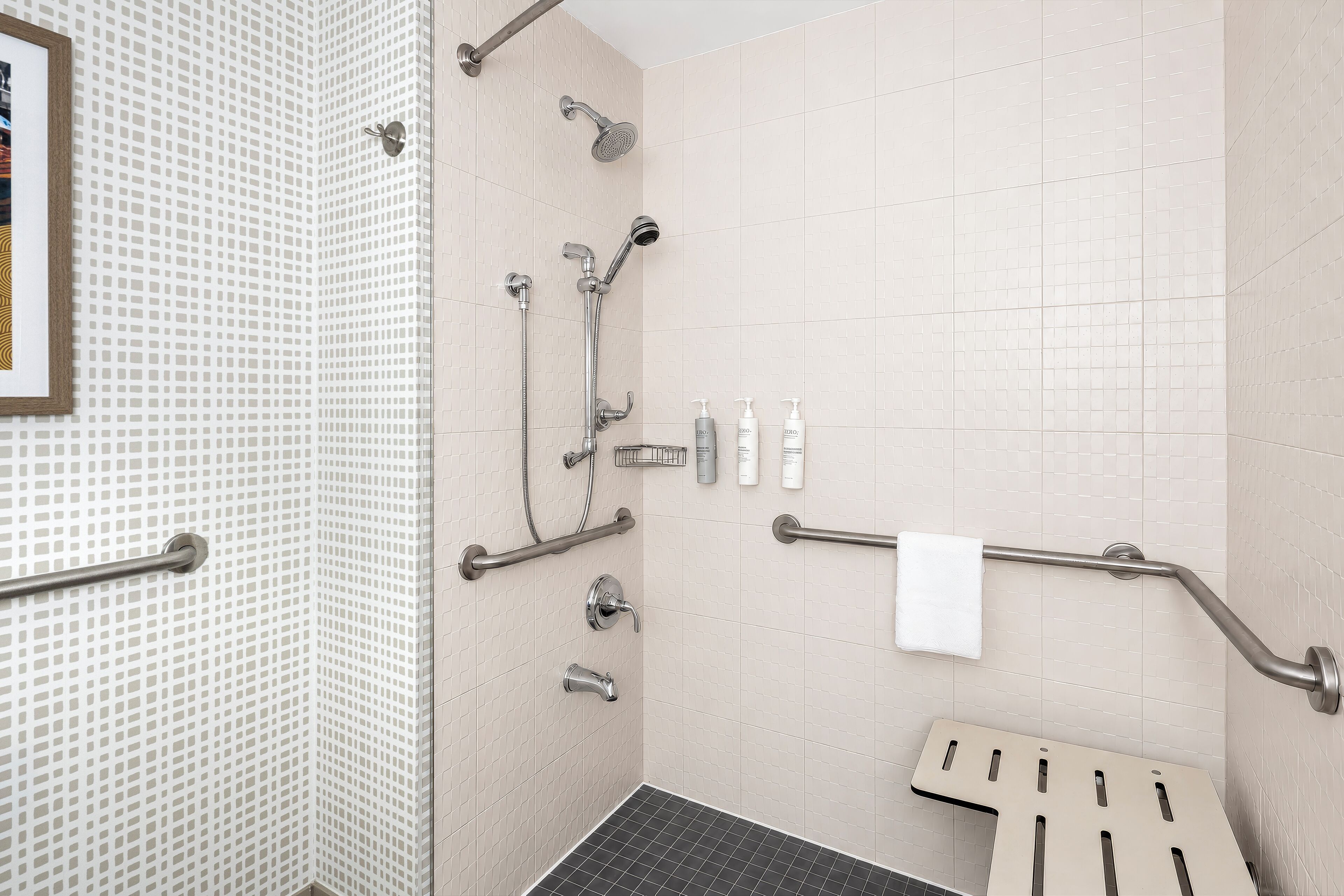 A bathroom with a shower, grab bars, and a towel rack.
