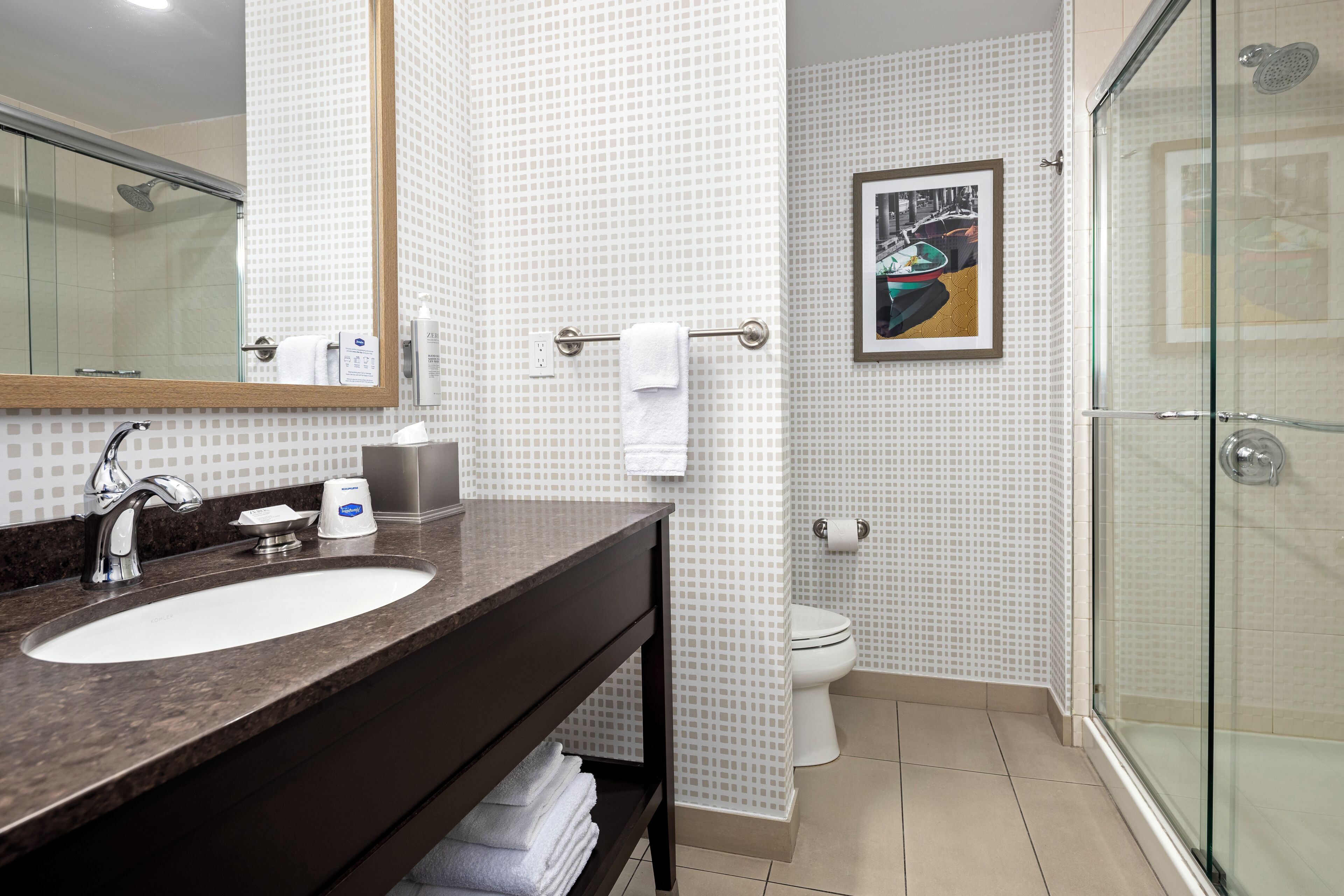 A bathroom with a sink, mirror, towel rack, toilet, and shower.