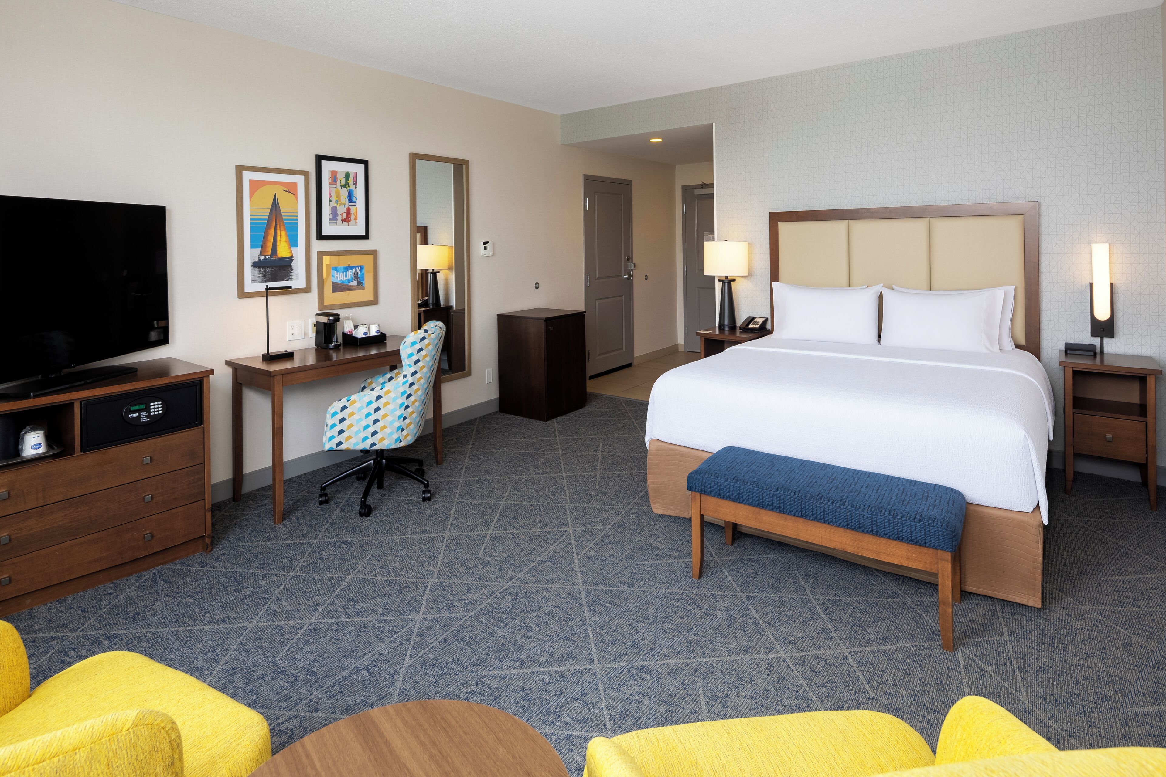 A hotel room with a bed, a desk, a chair, a television, and a bathroom.