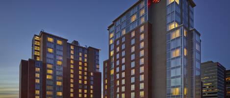 A hotel with multiple floors, a parking lot, and a clear sky.