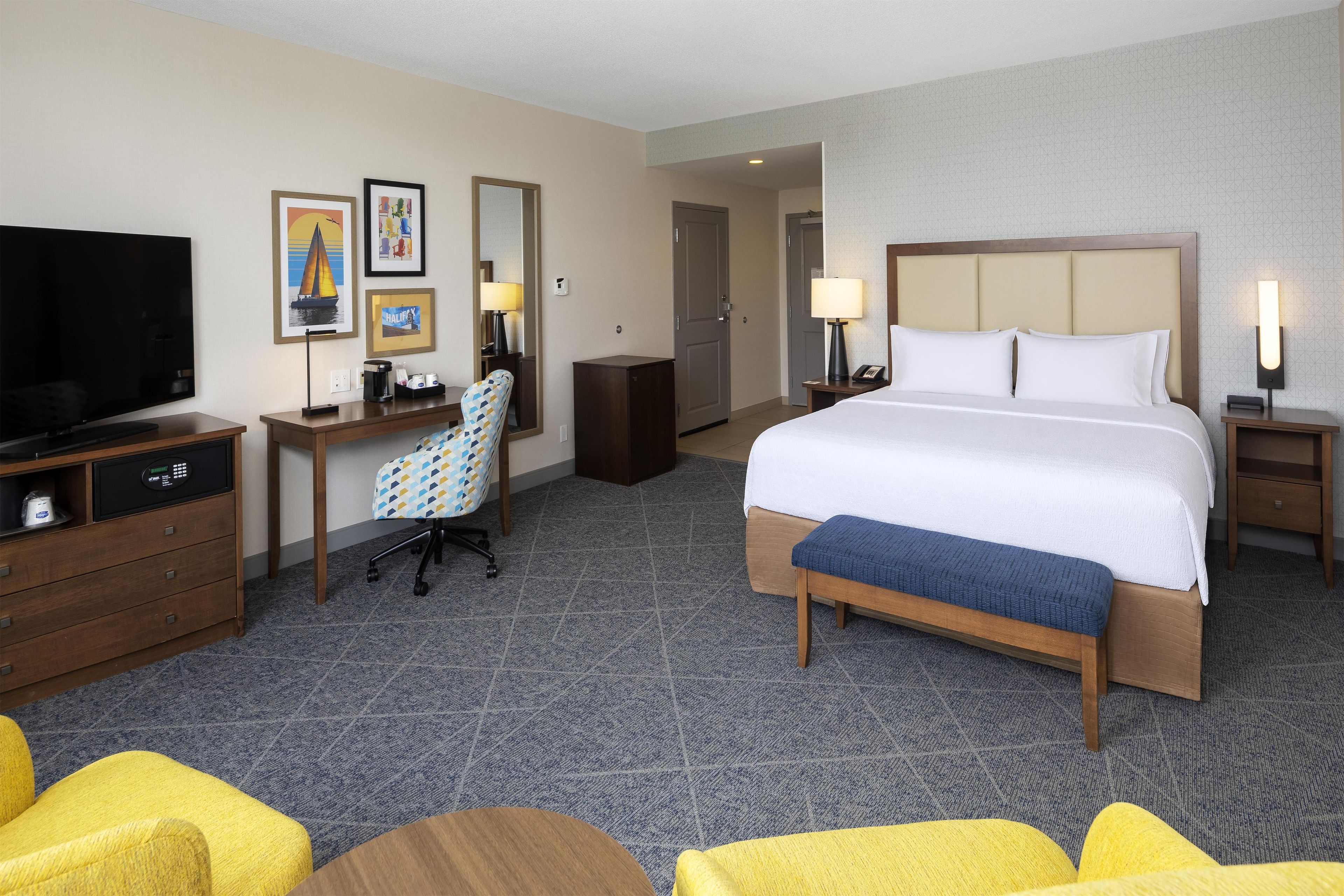 Una habitación de hotel con cama, escritorio, silla, televisor y baño.