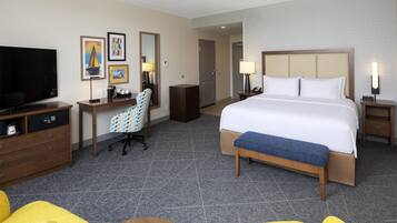 Una habitación de hotel con cama, escritorio, silla, televisor y baño.