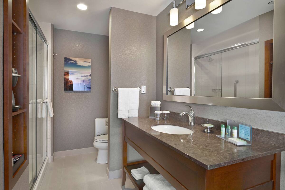 A modern bathroom with a large mirror, a sink, and a shower area.