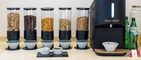 A yogurt dispenser with multiple containers of different toppings and a selection of bottled beverages.
