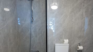 Een moderne badkamer met een glazen douchecabine, een wit toilet en een houten vloer.