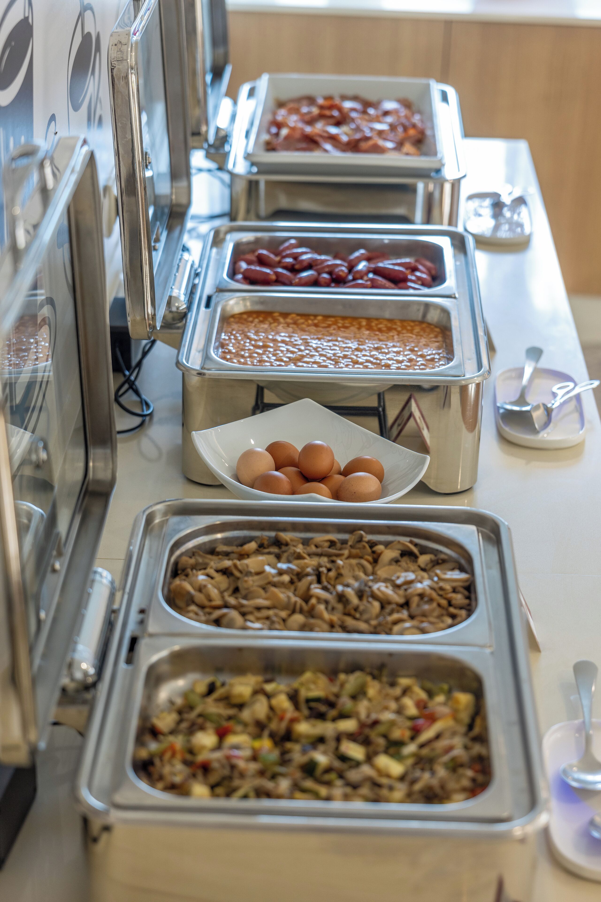 A buffet with various food options including eggs, sausages, and a casserole dish.