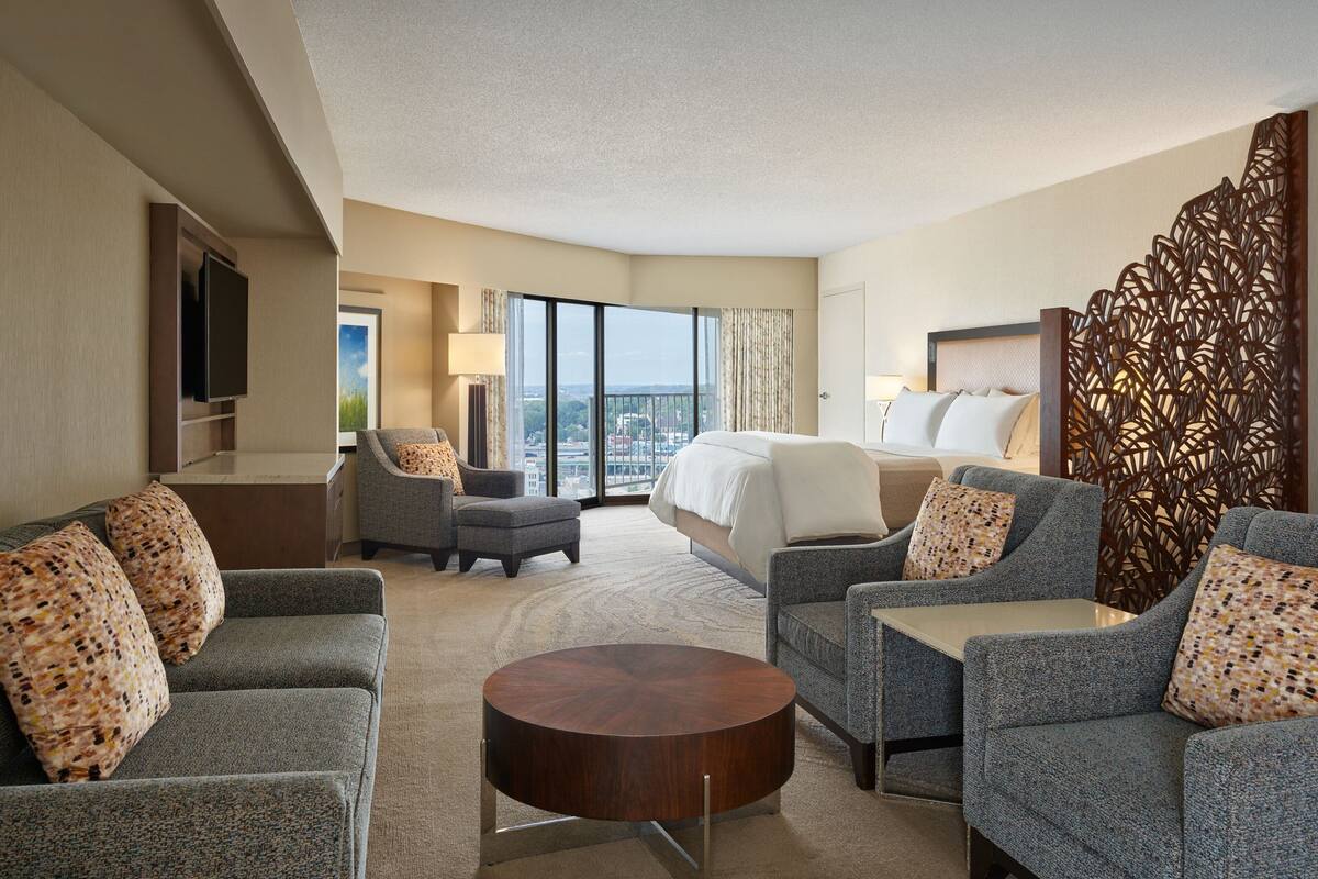 Ein Hotelzimmer mit einem großen Bett, zwei Sesseln, einem Sofa, einem kleinen Tisch und einem Fernseher.