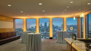 A modern hotel room with a city view, a bar area with bottles, and a seating area with a sofa and round tables. - The Westin Kansas City at Crown Center (Kansas City)