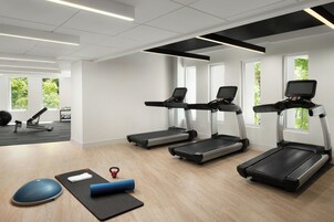 Un gimnasio moderno con cintas de correr, pelotas de ejercicio y colchonetas.