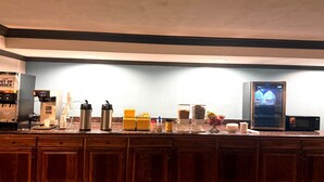 Un coin cuisine équipé d’une machine à café, de thermos, d’un réfrigérateur et d’un four à micro-ondes.