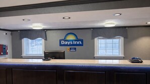 Un espace d’accueil avec une enseigne Days Inn, un ordinateur, une caisse enregistreuse et une fenêtre avec des stores.