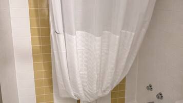 Un baño con bañera, inodoro y cortina de ducha.
