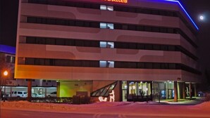 Un hotel a più piani dal design moderno, con un grande neon che riporta 'alex hotel & suites' e un ingresso con porte in vetro.